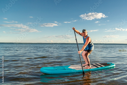 A man on a sup board against a clear blue sky. © finist_4