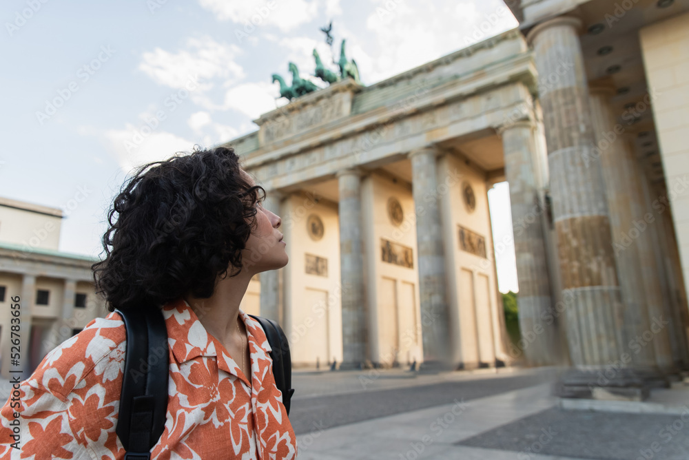 Fototapeta premium young traveler with backpack looking at brandenburg gate in berlin.