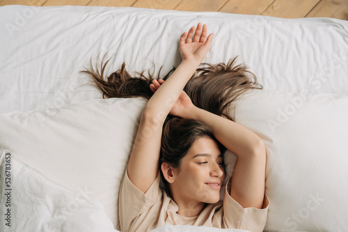 Photography Top view of young beautiful sleepy brunette woman resting in bed after waking up