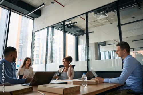 Meeting of young colleagues at table in big modern office