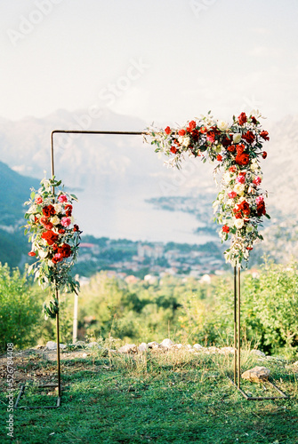 Valokuvatapetti Metal wedding arch decorated with flowers on top of a mountain above the bay