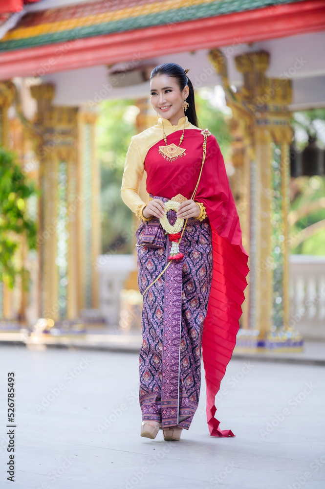 Attractive Thai woman in an ancient Thai dress holds a fresh garland paying homage to Buddha to make a wish on the traditional Songkran festival in Thailand