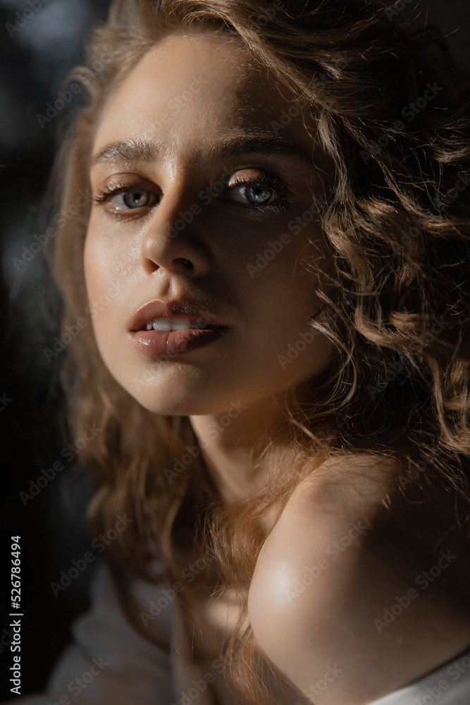 beautiful caucasian girl bride with curly red and blue eyes hair sits in a wedding dress and look at the camera. fashion portrait