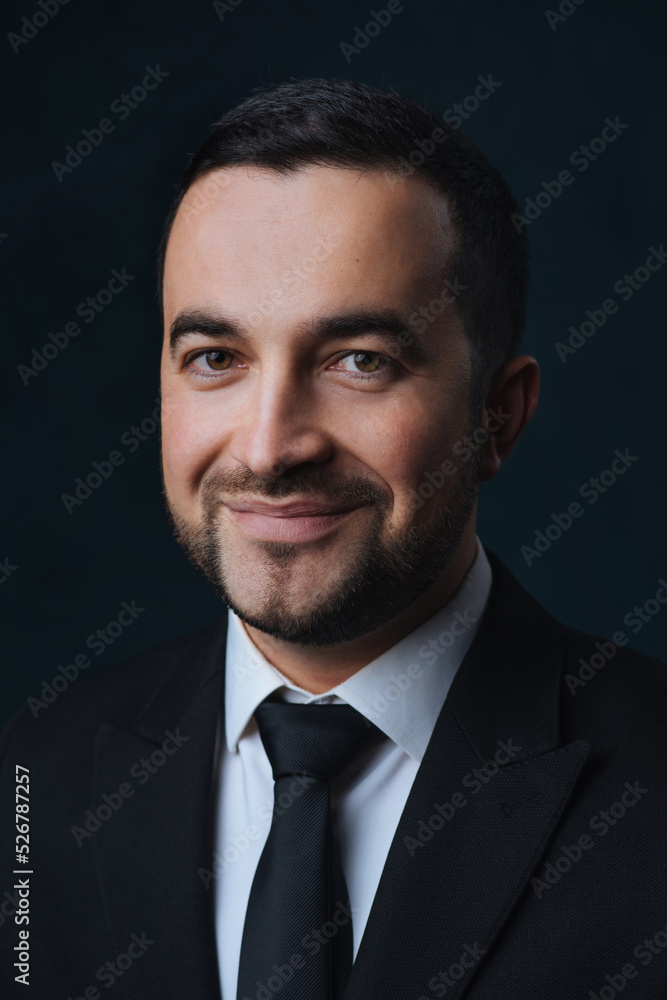 Close-up portrait of a smiling modern man in a fashionable suit, a man in a black suit on a dark background Close-up portrait of a smiling modern man in a fashionable suit, a man in a black suit on a dark background