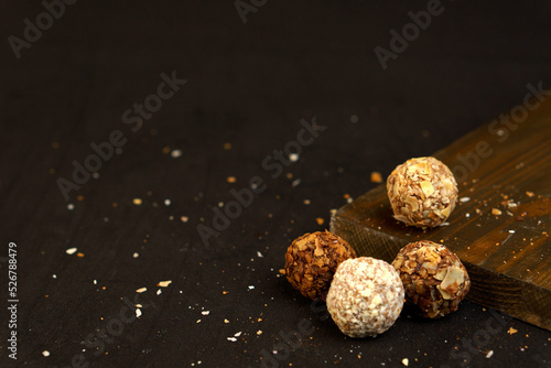 Four round truffle candies on a wooden board. Confectionery crumb.Dark background with place for text.