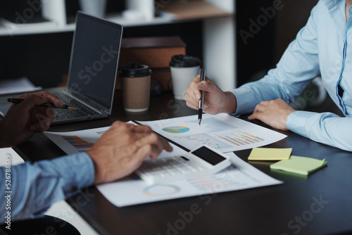 The business team jointly plan the investment at the meeting. Close-up of business advisor pointing to graph and analyzing financial report, balance sheet, financial statement.