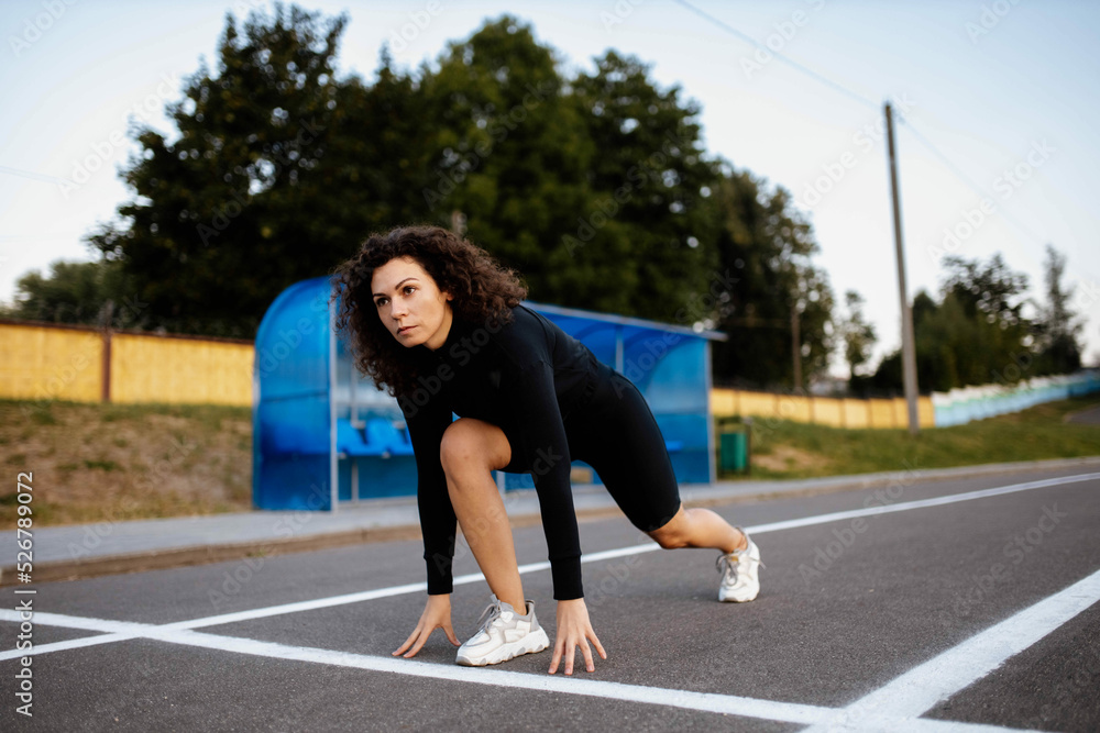 young woman athlete in stock at the start before running. Curly athletic woman runner young woman athlete in stock at the start before running. Curly athletic woman runner