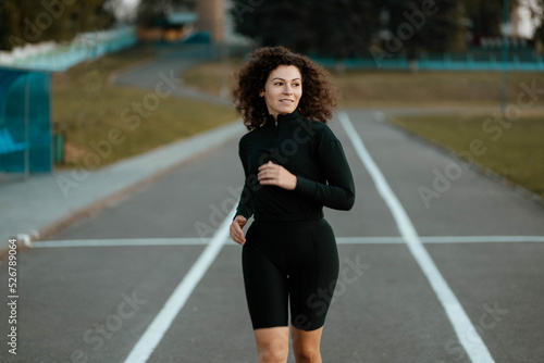 young athletic woman runs in training in black sportswear.