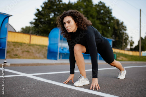 young woman athlete in stock at the start before running. Curly athletic woman runner