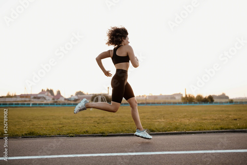 young sports woman runs in the stadium in sportswear, sportswoman training.