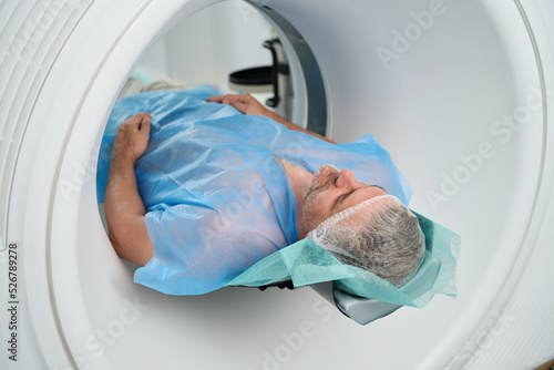 фотографія Man lies in tomograph chamber on diagnosis abdomen in medical center