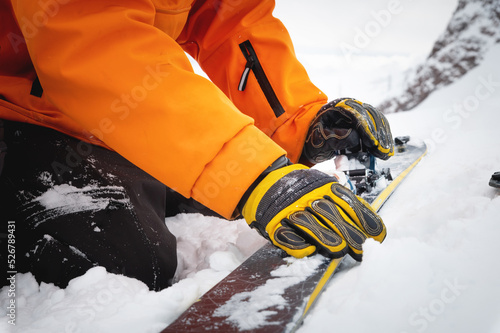Photos Close-up of a man's hand, adjusting the skis against the background of snow and things, putting on the skins on the track
