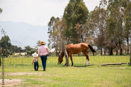 Niños vaqueros caminando en el campo hacia un caballo 