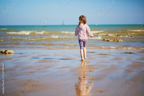 Preschooler girl playing on the sand beach at Atlantic coast of Normandy, France