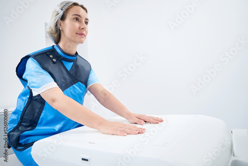 Woman in lead shield keeps her hands on the machine