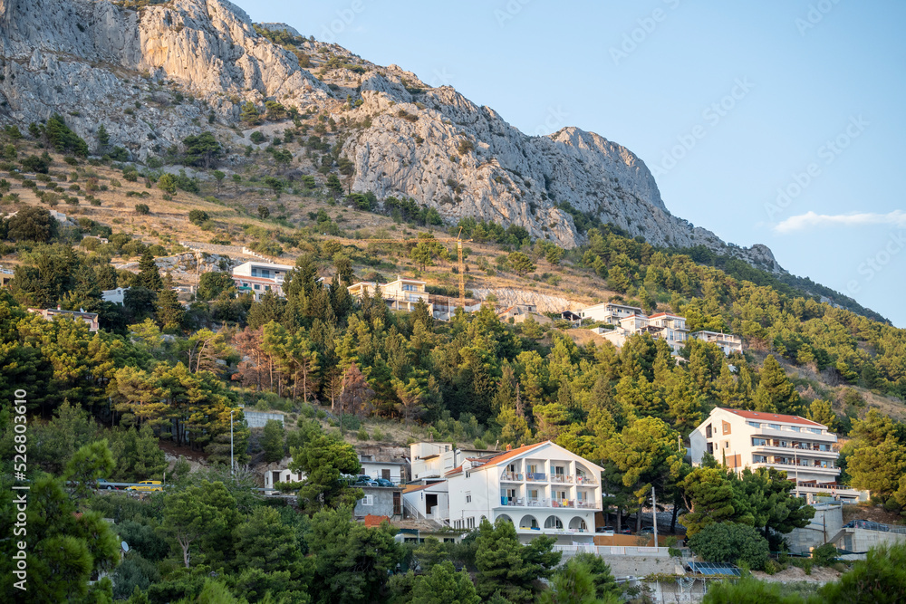 Rows of houses built on the steep slopes of Dinara mountain and its rocky cliffs towering over the village