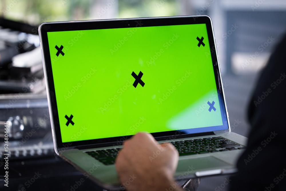 Car service mechanic uses laptop computer with green screen mock up ...