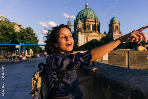 BERLIN, GERMANY - JULY 14, 2020: amazed young woman pointing away near blurred berlin cathedral. photo