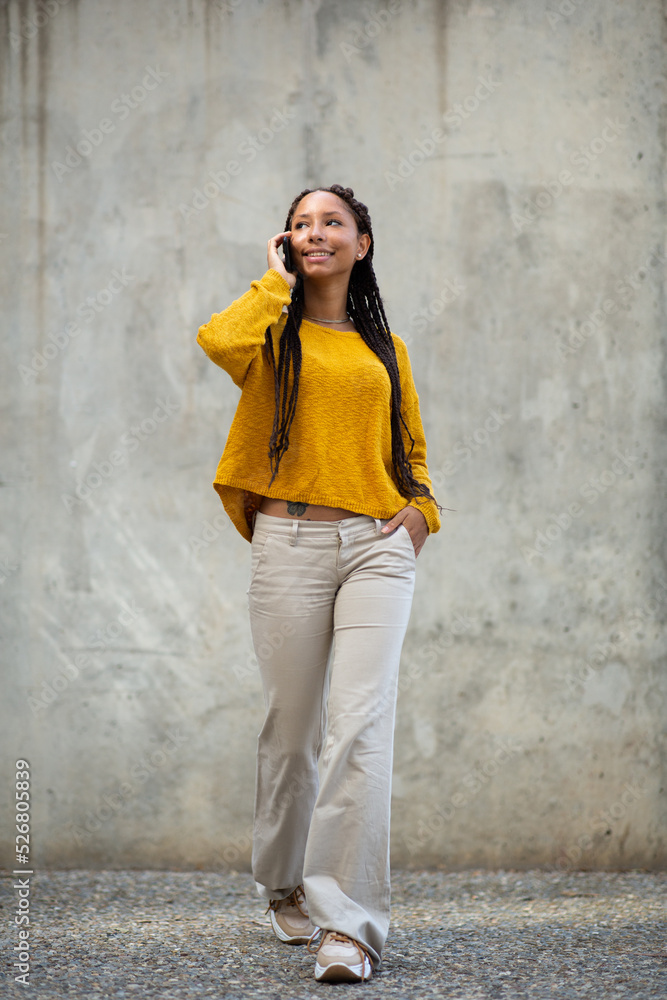 Obraz premium Beautiful young black woman walking outside talking on her mobile phone