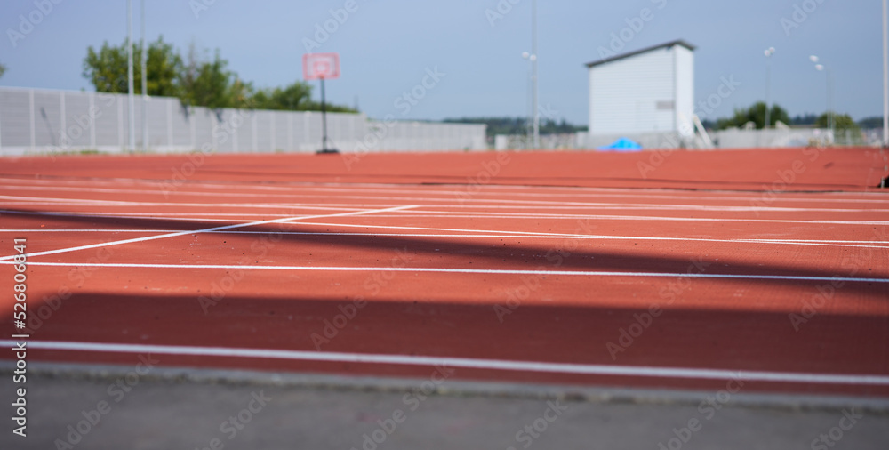 Running track. Red treadmill at the stadium with white lines.