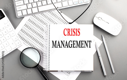 CRISIS MANAGEMENT text on notepad on chart with keyboard and calculator on grey background