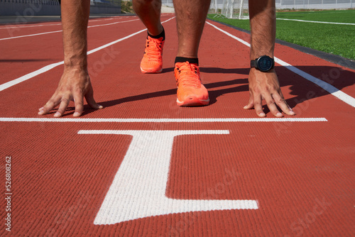 Hands on the starting line, the sprinter is preparing to start at the stadium.