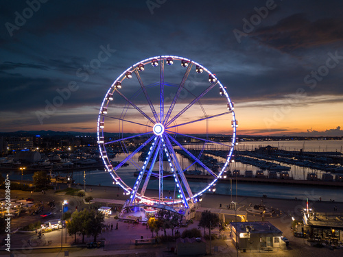 Italy, August 2022: view of the ferris wheel of Rimini with all the colored lights near the beach of the Romagna Riviera
