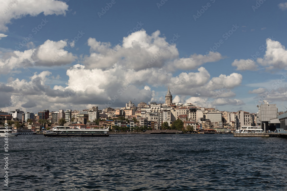 View of tour boats on Golden Horn area of Bosphorus in Istanbul. Galata tower and Beyoglu district are in the background. It is a sunny summer day.
