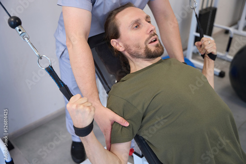 Weakened man is engaged in special equipment under supervision doctor