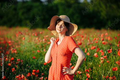 beautiful girl in a red dress on the background of a field of red poppies © Andrii