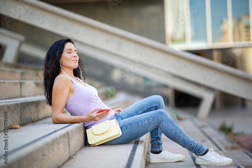 Carefree woman listening music outdoors on staricase photo