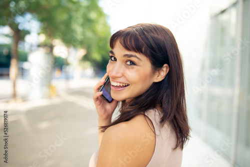 Beautiful young woman talking on cellphone in city