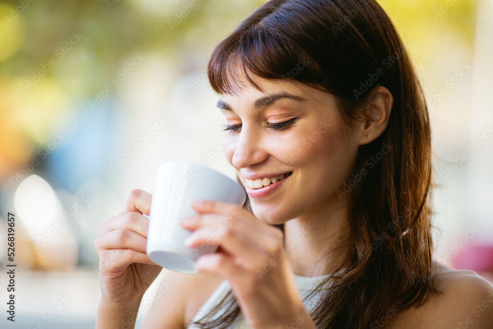 Beautiful young woman drinking coffee at cafe and smiling Beautiful young woman drinking coffee at cafe and smiling