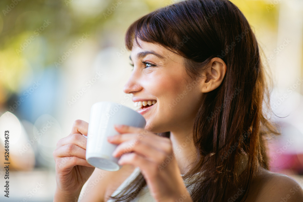 Smiling young woman drinking coffee at cafe Smiling young woman drinking coffee at cafe