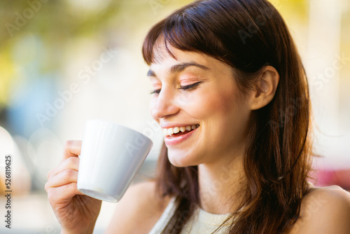 Happy young woman drinking coffee at cafe