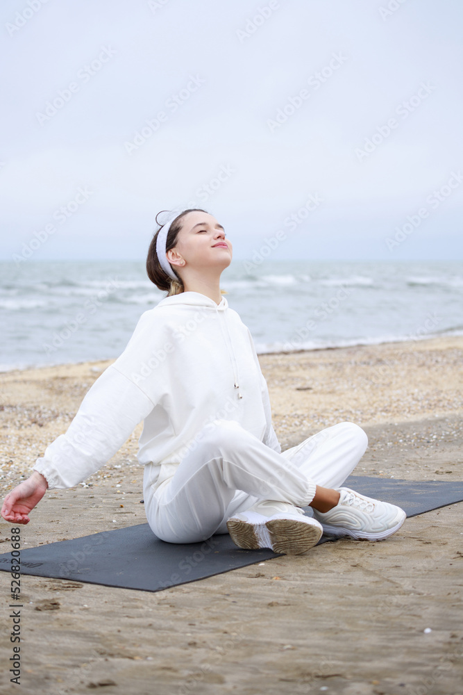 Vertical photo of young athlete sittin on the mat and doing meditation