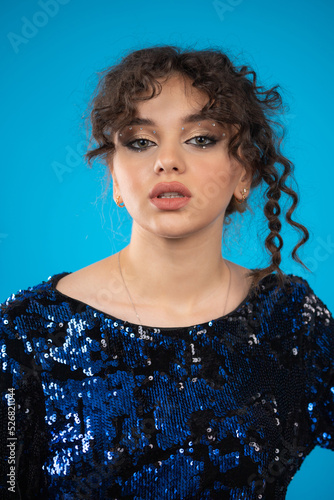 Close-up photo of young curly-haired girl on blue background