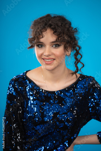 Cheerful young curly-haired girl wearing gilded dress and smiling