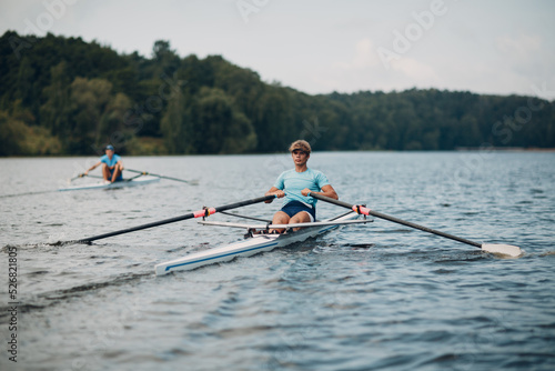 Sportsman oarsman single scull man rower rowing on boat oars. photo