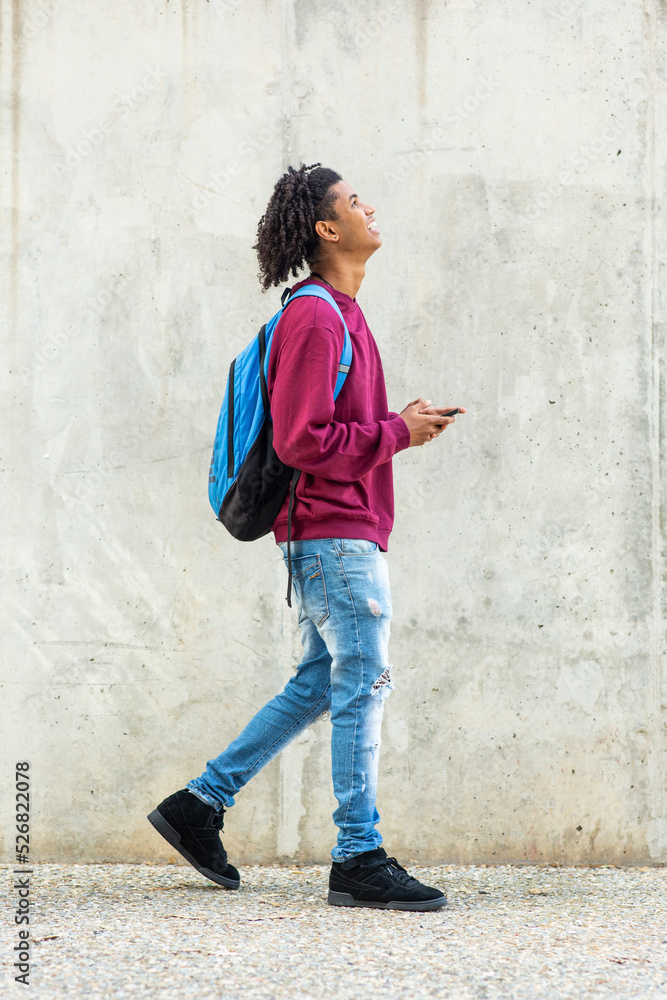 Man looking up while walking with mobile phone and backpack Man looking up while walking with mobile phone and backpack