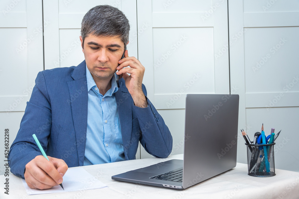 Man in suit sitting near laptop working remotely Man in suit sitting near laptop working remotely