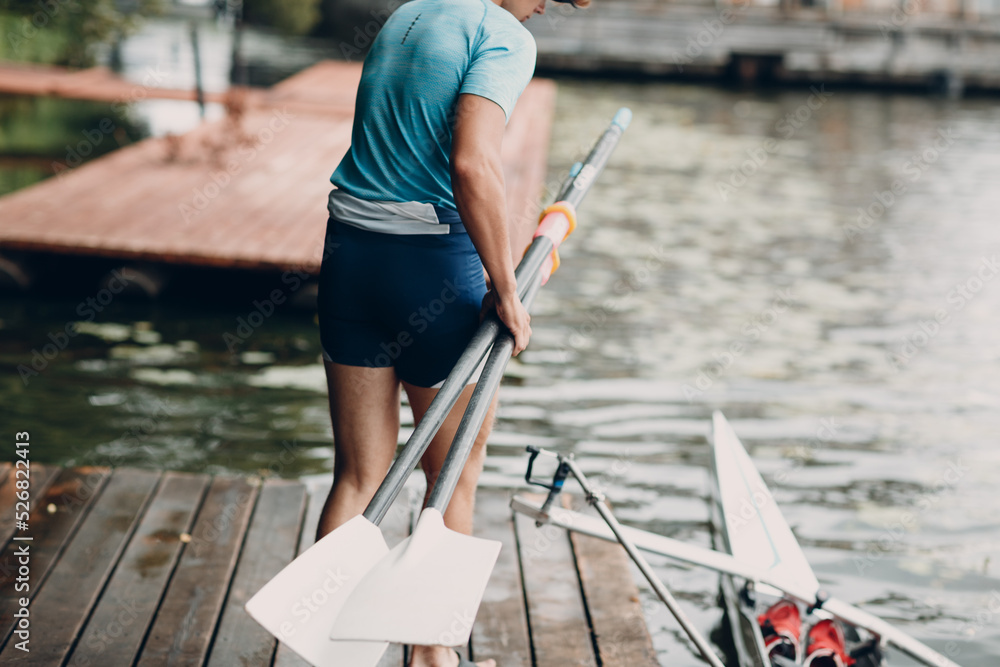 Sportsman single scull man rower prepare to competition with boat on pier