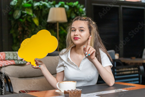 Young beautiful lady holding yellow idea board and pointing her finger up