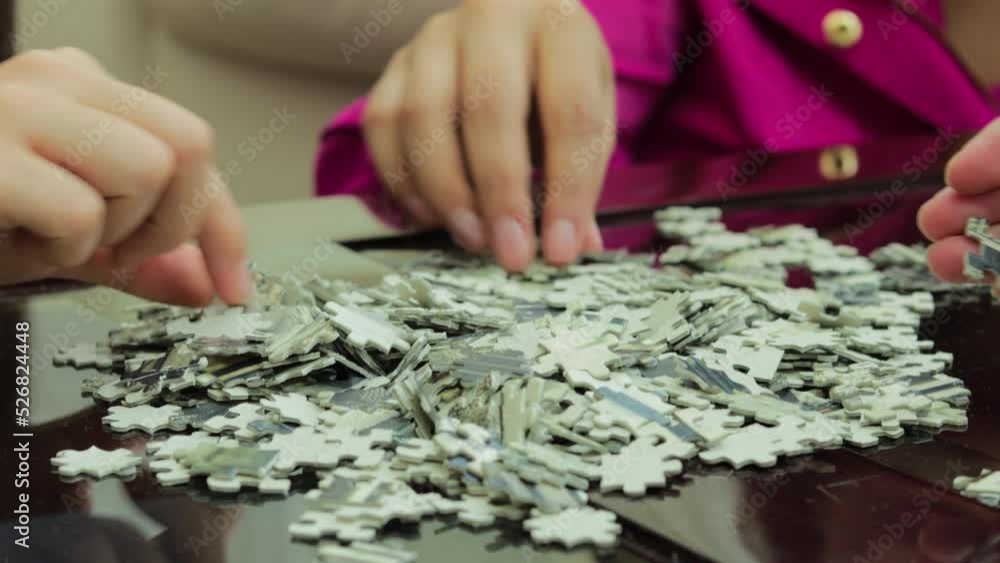 Hands of unrecognizable women doing a puzzle Hands of unrecognizable women doing a puzzle