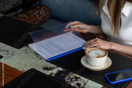 Female hands holding notebook beside of cup of coffee