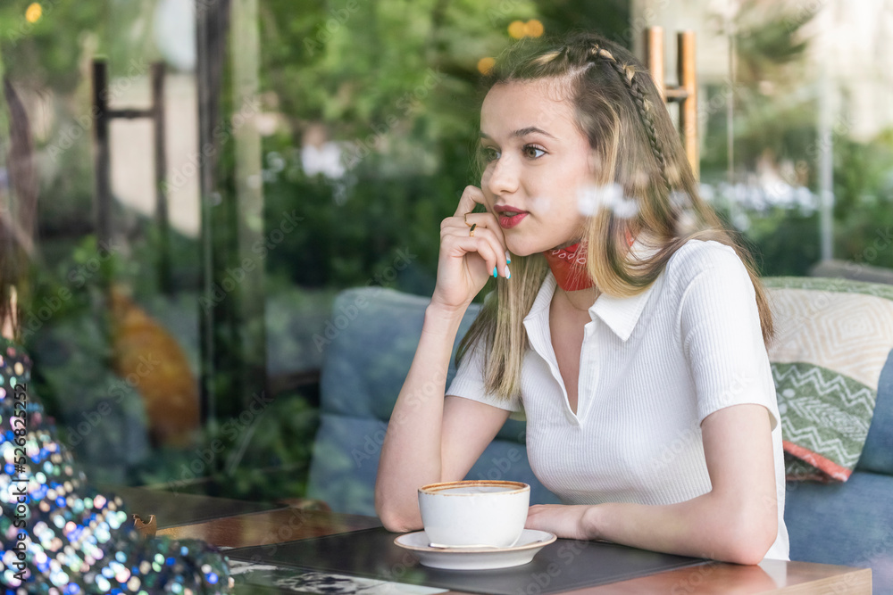 cute lady sitting at the cafe and looking at her friend cute lady sitting at the cafe and looking at her friend