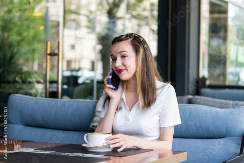 Young girl sitting at the restaurant and talking on the phone Free Download Young girl sitting at the restaurant and talking on the phone - GFXLoad