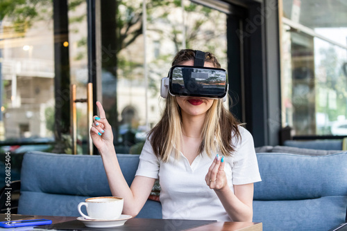 Cute lady wearing VR set and pointing her finger aside at the restaurant photo