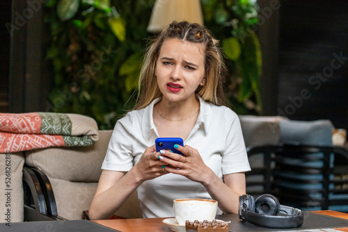 Beautiful lady holding phone at looking at the camera at the restaurant. photo