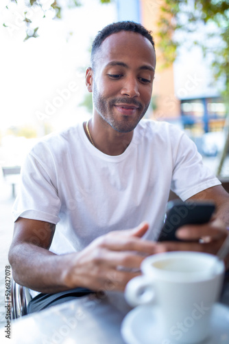 Man sitting with mobile phone and coffee cup at outdoor cafe